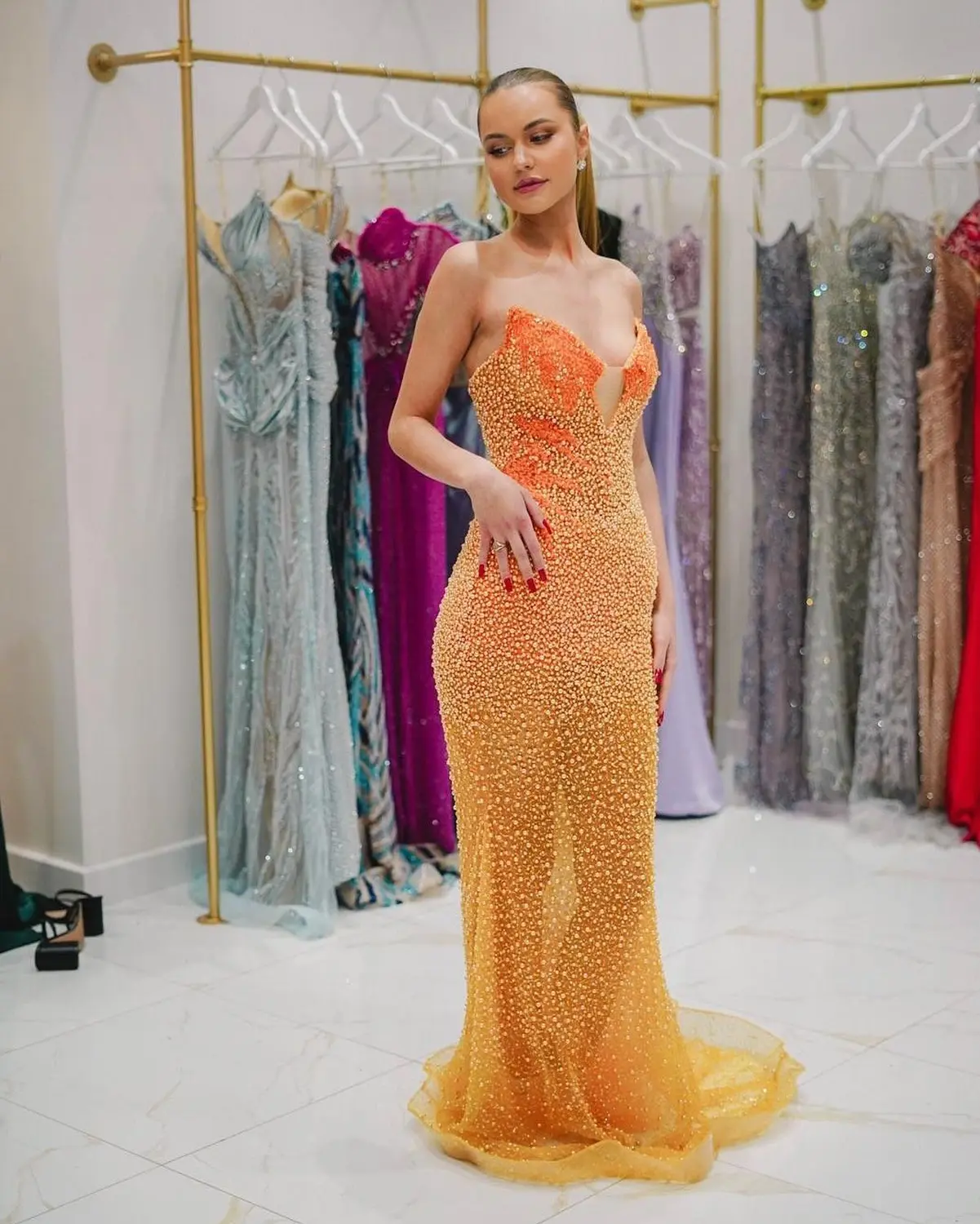 Kleid des V&E-Models, das ein orangefarbenes Kleid mit Silberstickerei trägt