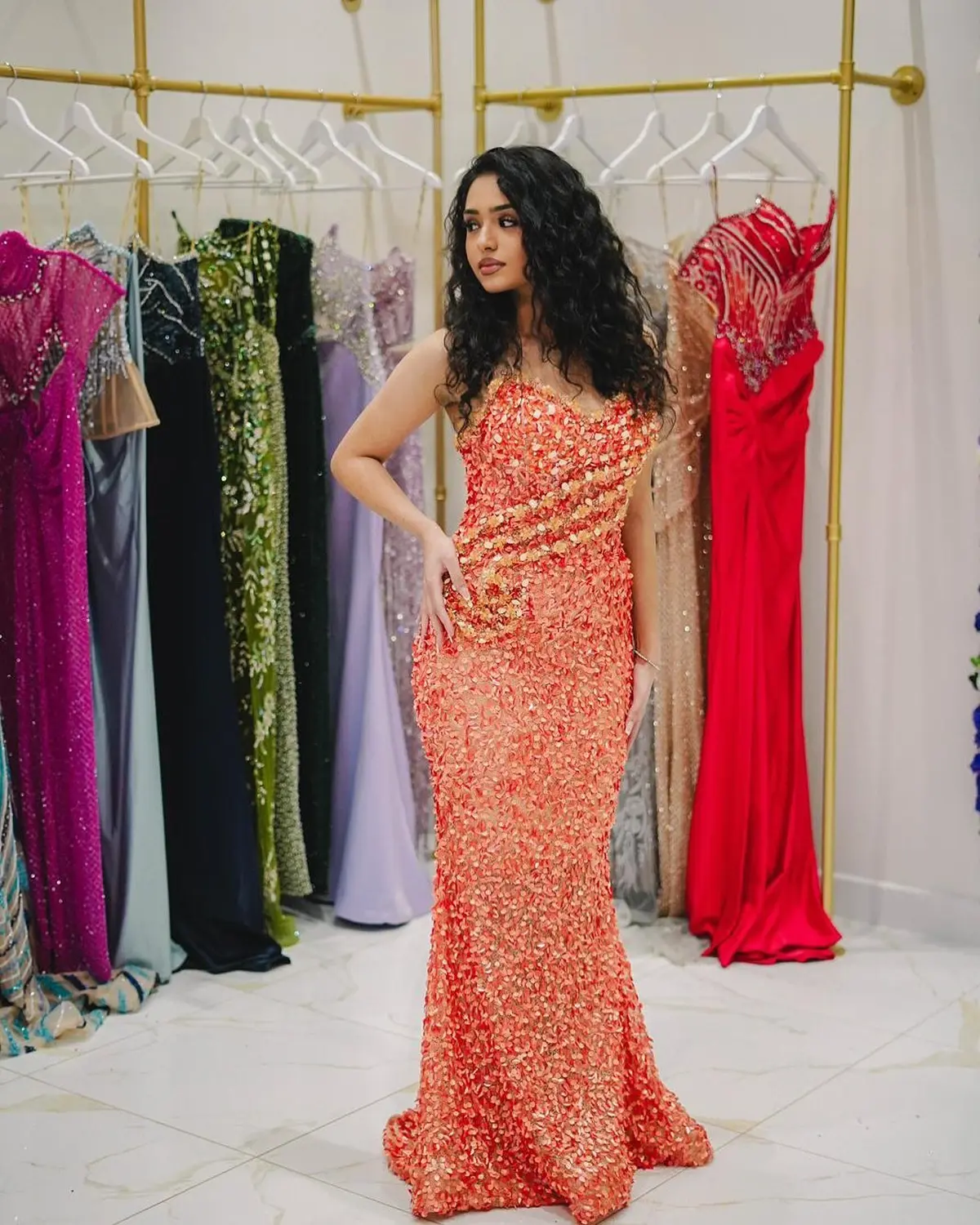 Kleid des V&E-Models, das ein orangefarbenes Kleid mit gelben Perlen trägt